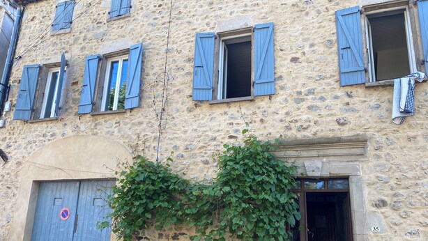 A stone building with multiple windows, a door with a no parking sign, and a number '35' on the wall.