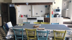 A dining area with a checkered tablecloth, blue and yellow chairs, a white stove, and a blue microwave.
