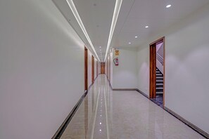A long, well-lit corridor with a polished floor, wooden doors, and a staircase on the right. - Townhouse Skyboat XLO Point (Nashik)