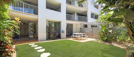 A modern multi-story building with a well-maintained lawn and outdoor seating area.