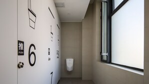 Un baño moderno con puertas numeradas, un secador de manos y una ventana.