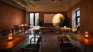 Una sala de conferencias con mesas, sillas, una pantalla de proyector y una guitarra.