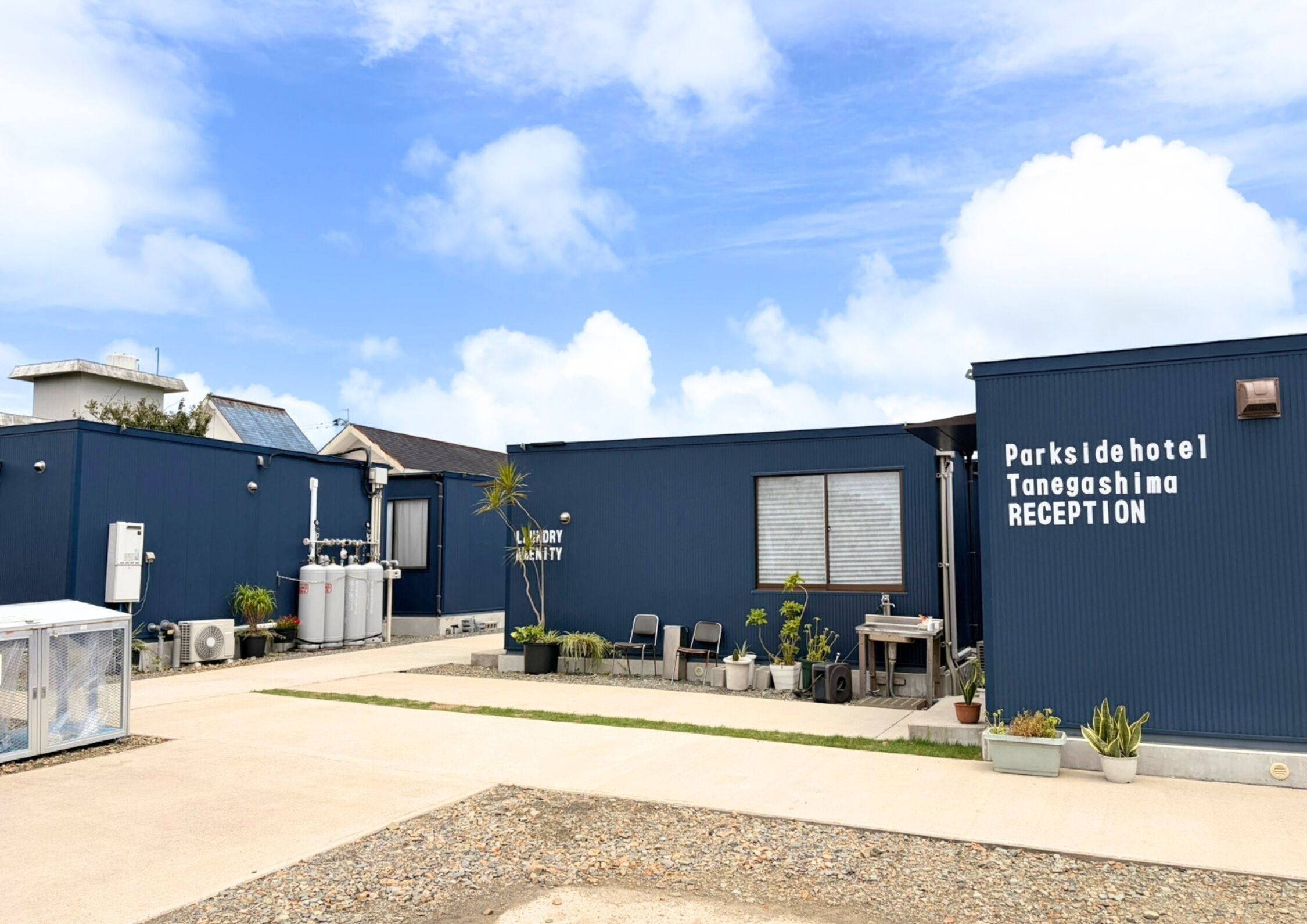 A reception area with a sign for 'Parkside Hotel Tanegashima Reception' and a building with a blue exterior.