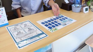 Una recepción de hotel con folletos informativos, un reloj digital y una planta.