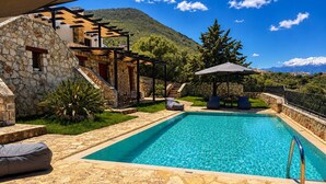 A swimming pool with stone flooring, outdoor seating, and a stone building with a pergola. - Hidden Oasis Amazing Seaview - Kalisti 1BD 1BA 4PL (Kokkino Chorio city)