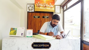 A reception desk with a sign that reads 'RECEPTION,' a calendar, a box of tissues, and a laptop. - Perfect 5-bedroom hotel with AC in pleasant Varanasi (Varanasi)