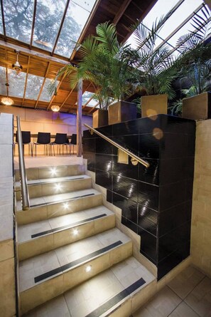 Eine Treppe mit schwarzen Fliesen, einem Metallgeländer und einer Glaskuppel mit Tageslicht.