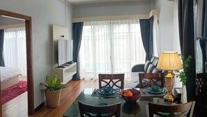 A modern hotel room with a dining area, a TV, and a window with curtains. - Villa Escape , Aonang Krabi (Meung krabi)