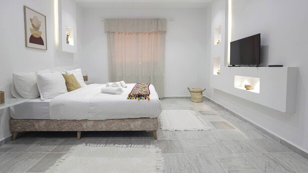 Ein modernes Schlafzimmer mit Bett, Nachttischen, einem Fernseher und integrierten Regalen.
