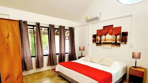 A bedroom with a bed, curtains, a wall-mounted air conditioner, a nightstand, and a painting. - Peaceful family house Destiny Homes (Pocosol)