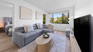 A modern living room with a grey sofa, a wooden coffee table, and a black TV stand. - 15 Calm & Cosy w Parking - Walk to Beach & Train (Mosman Park)
