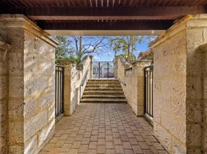 Una escalera de piedra que lleva a un espacio cubierto con vistas a árboles y un cielo despejado.