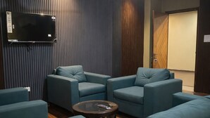 Un salon moderne doté d’un téléviseur à écran plat, d’un ventilateur de plafond et d’une grande fenêtre.