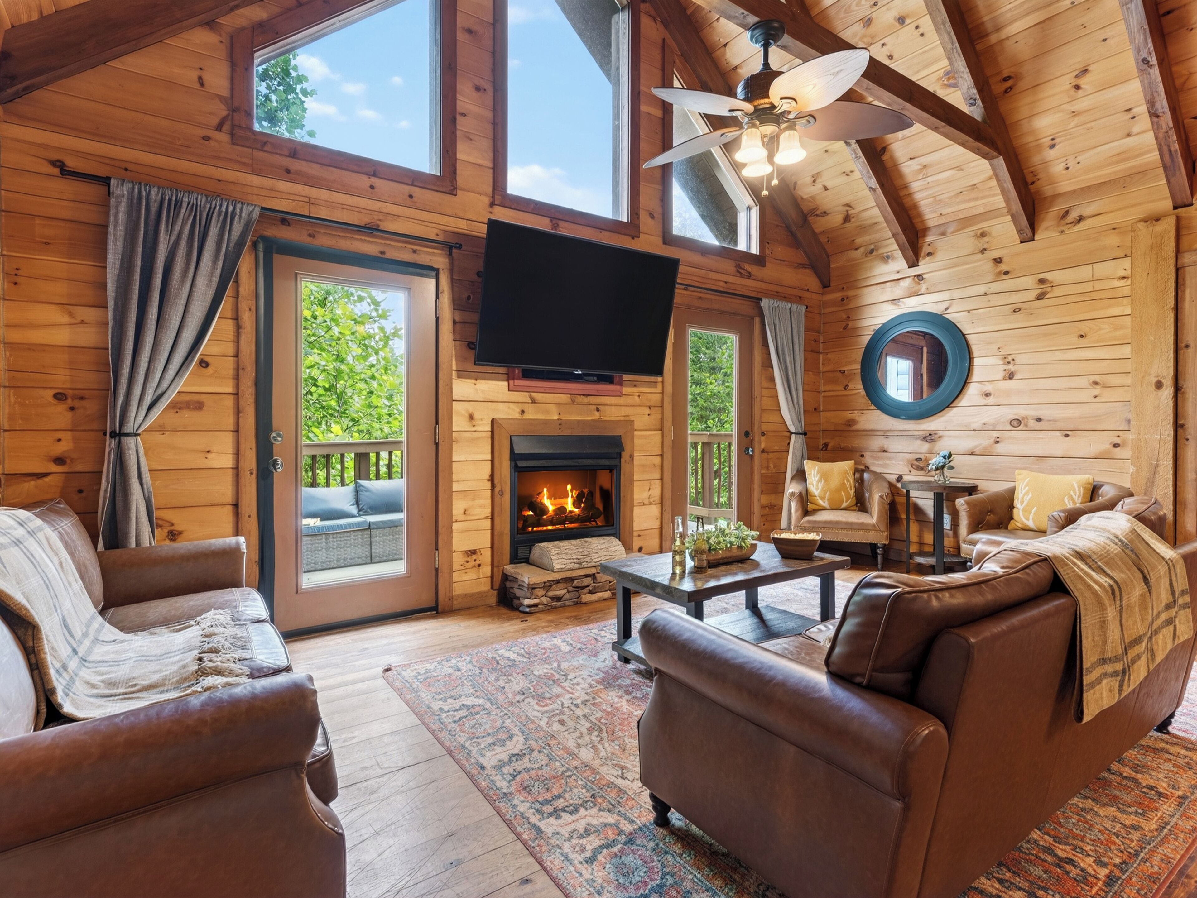 Cozy cabin living with vaulted wood ceilings, a fireplace, and direct deck access for relaxing mountain downtime.