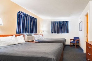 A hotel room with two beds, a chair, a dresser, and a window with curtains.
