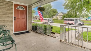 Eine überdachte Veranda mit roter Tür, einer aufgehängten US-amerikanischen Flagge und einem Metallgeländer.