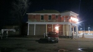 A two-story building with a balcony, a parked car, and a streetlight. - Five Mile Hotel - America's Most Famous Roadhouse (Butte)