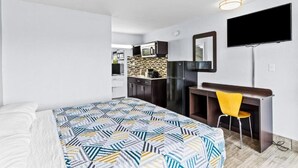 A modern room with a bed, a desk, a chair, a TV, and a kitchenette. - King Bed|Mobil Acc|Tub|Nsmk|Kitchen (Wilmington)