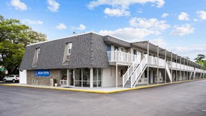 A motel with a 'NOW OPEN' sign, a covered outdoor area with stairs, and a parking lot. - 1 King Bed|Nsmk,Kitchen (Wilmington)