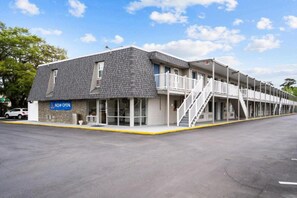 A motel with a 'NOW OPEN' sign, a covered outdoor area with stairs, and a parking lot. - 1 Queen Bed|Nsmk,Kitchen (Wilmington)