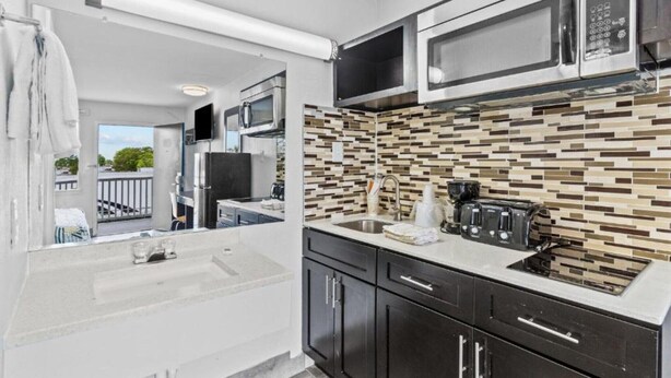 A compact kitchen with a microwave, toaster, and sink.