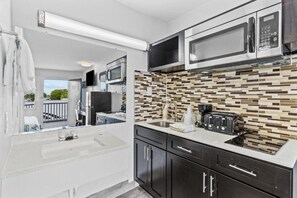 Una cocina compacta con microondas, tostadora y pileta.