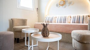 A cozy room with a bed, two white round tables, a woven basket, and a window with a curtain. - SolMare Premium Suite (Mastihari)