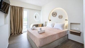 A modern hotel room with a large bed, a TV mounted on the wall, and a balcony with curtains. - SolMare Premium Suite (Mastihari)