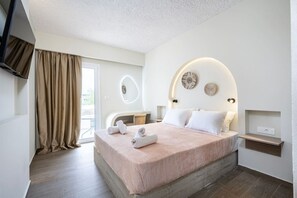 Ein modernes Hotelzimmer mit einem großen Bett, einem an der Wand montierten Fernseher und einem Balkon mit Vorhängen.