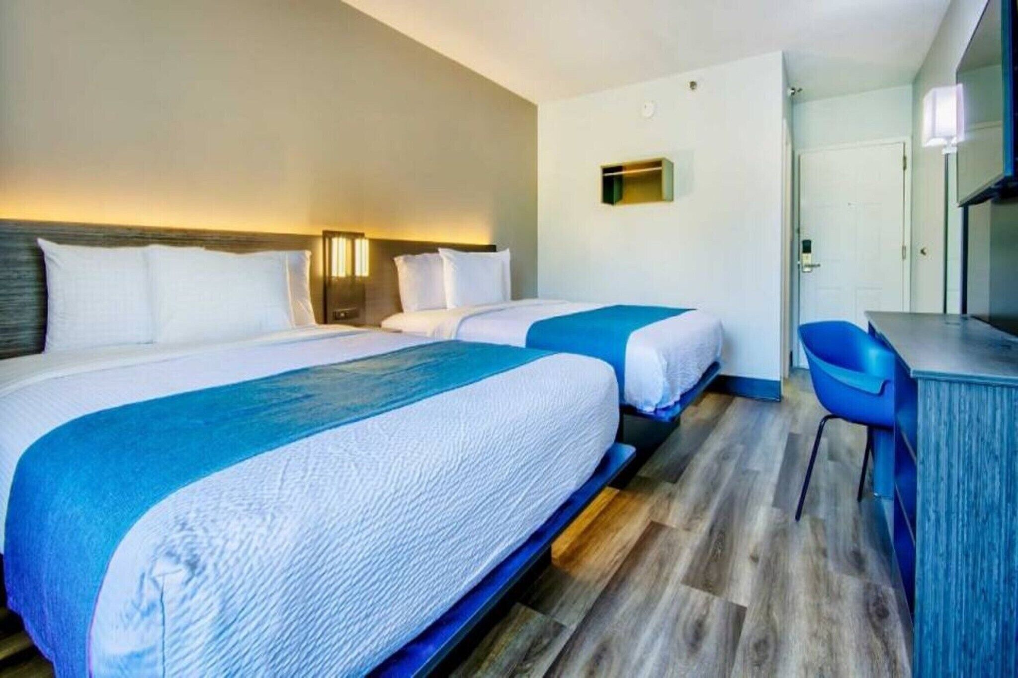 Une chambre d’hôtel avec deux lits, un bureau et une chaise.