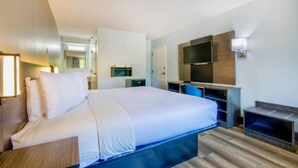 Una camera d'albergo con un letto, una scrivania, una televisione e uno specchio.