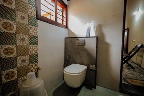 A small bathroom with a toilet, a shower, and a sink. - Akruthi Palm Pavilion Resort (Chikkamagaluru)