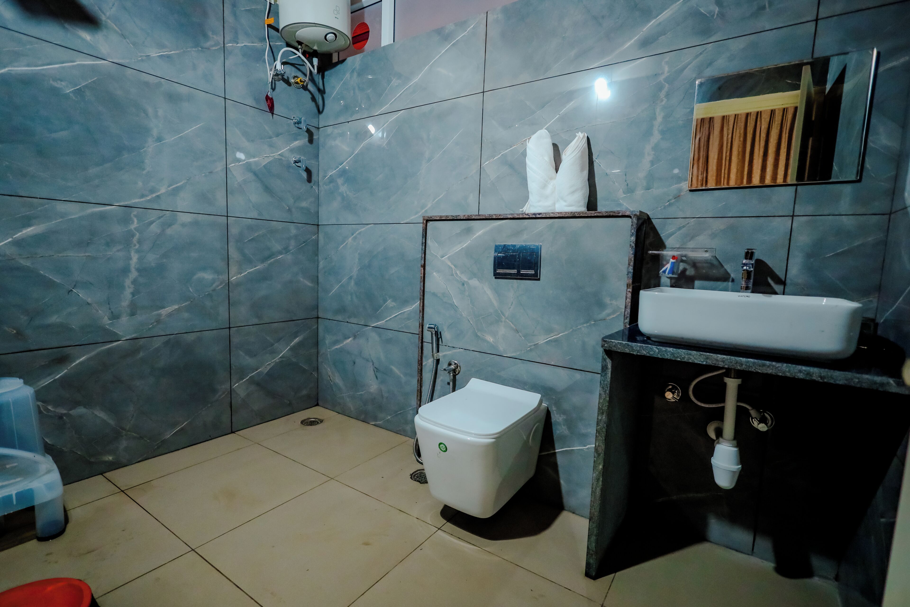 Une salle de bain comprenant des toilettes, un bidet, un lavabo et un miroir.