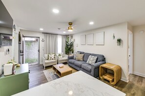 Ein modernes Wohnzimmer mit einem Marmor-Couchtisch, einem grauen Sofa und einem Holztisch.