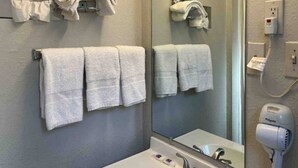 Un bagno con lavandino, specchio, portasciuga e asciugacapelli.