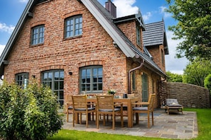 A brick house with a patio, outdoor furniture, and a garden. - Haus Juwel von Wenningstedt - Moin and welcome to the,,Juwel von (Wenningstedt-Braderup (Sylt))