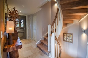 A modern interior with a wooden staircase, a door with a window, and a wall-mounted light fixture. - Haus Juwel von Wenningstedt - Moin and welcome to the,,Juwel von (Wenningstedt-Braderup (Sylt))