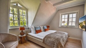 Une chambre à coucher avec un lit, une chaise, une lampe et un tableau au mur.