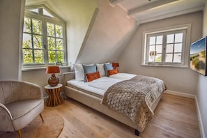 A bedroom with a bed, a chair, a lamp, and a painting on the wall. - Haus Juwel von Wenningstedt - Moin and welcome to the,,Juwel von (Wenningstedt-Braderup (Sylt))