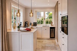 A kitchen with a large island, a wine cooler, and a view of greenery outside. - Haus Juwel von Wenningstedt - Moin and welcome to the,,Juwel von (Wenningstedt-Braderup (Sylt))