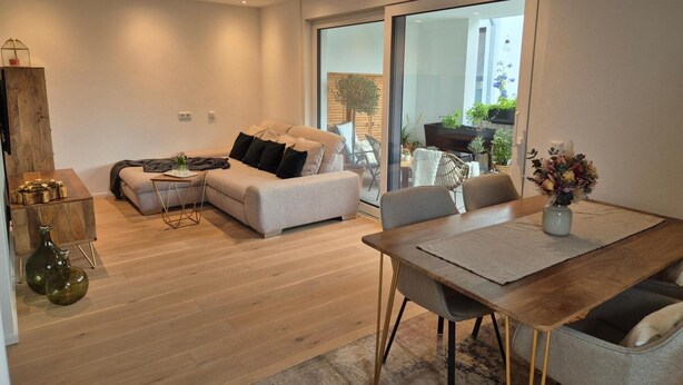 A modern living room with a sofa, coffee table, and dining area. - Premium Lake Constance Base Apartment – Modern, Cozy & Well-Maintained (Rielasingen-Worblingen)