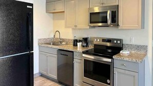 Una cocina moderna con electrodomésticos de acero inoxidable, encimeras de granito y armarios de tonos claros.