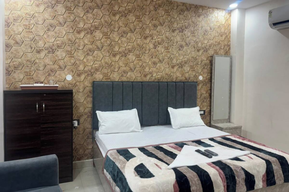 A bedroom with a bed, a dresser, a mirror, and a wall with a hexagonal pattern.