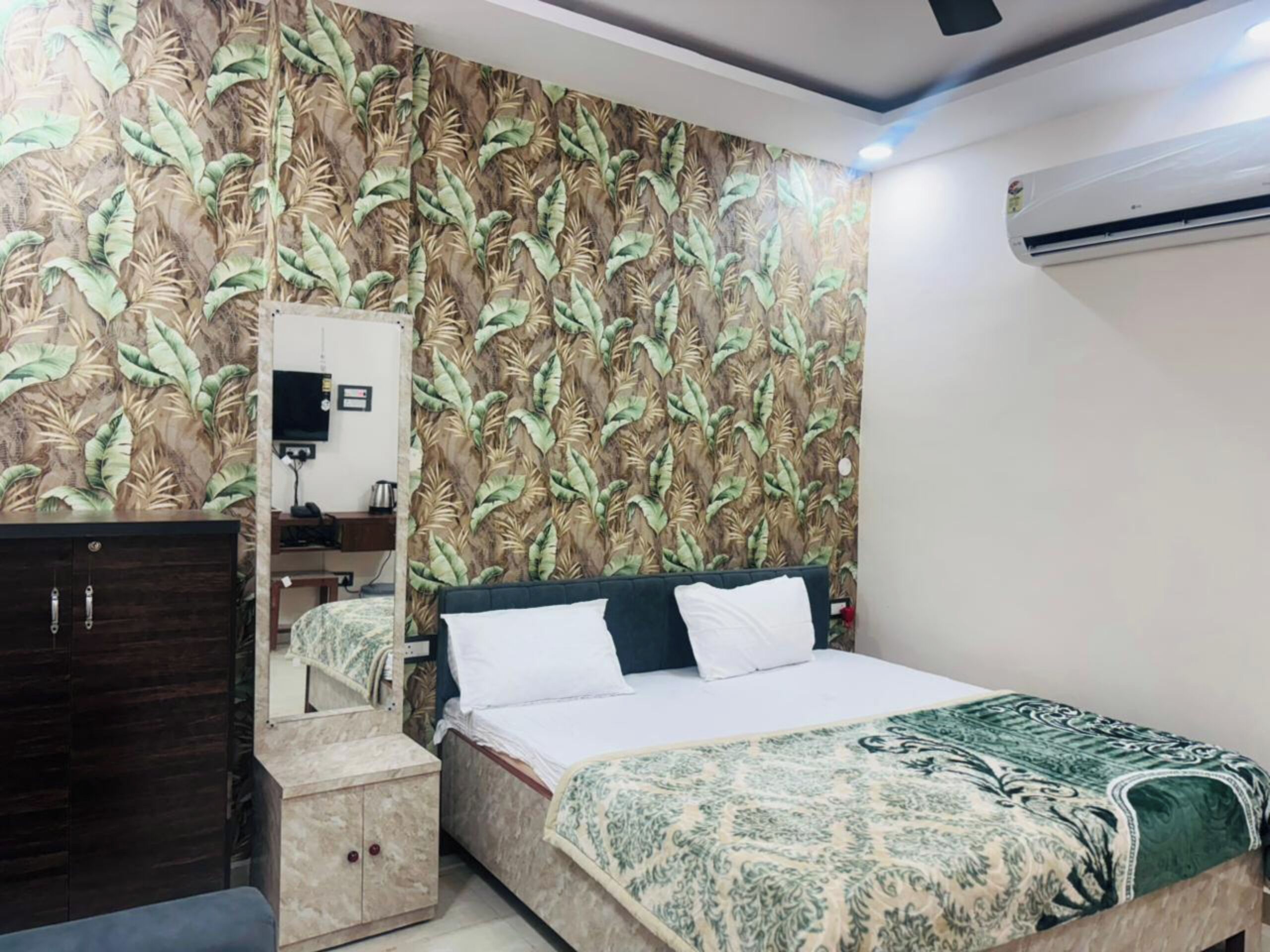 A bedroom with a bed, a dresser, a mirror, and a wall-mounted air conditioner.
