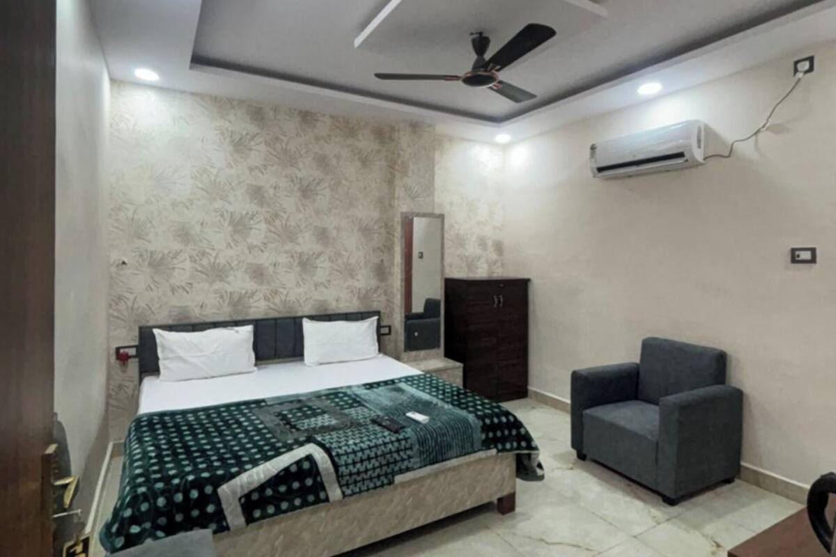 A bedroom with a bed, a desk, a chair, a ceiling fan, and an air conditioning unit.