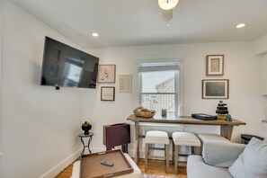 A living room with a TV, a dining area with a table and chairs, a sofa, and a window with a view of a building. - Walkable + Convenient! 1st-Floor Apt in Middletown (Middletown)