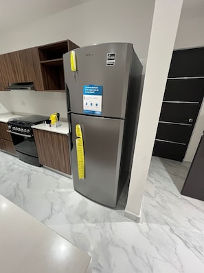 Eine moderne Küche mit Edelstahlkühlschrank, Holzschränken und einer Marmarbeitebene.