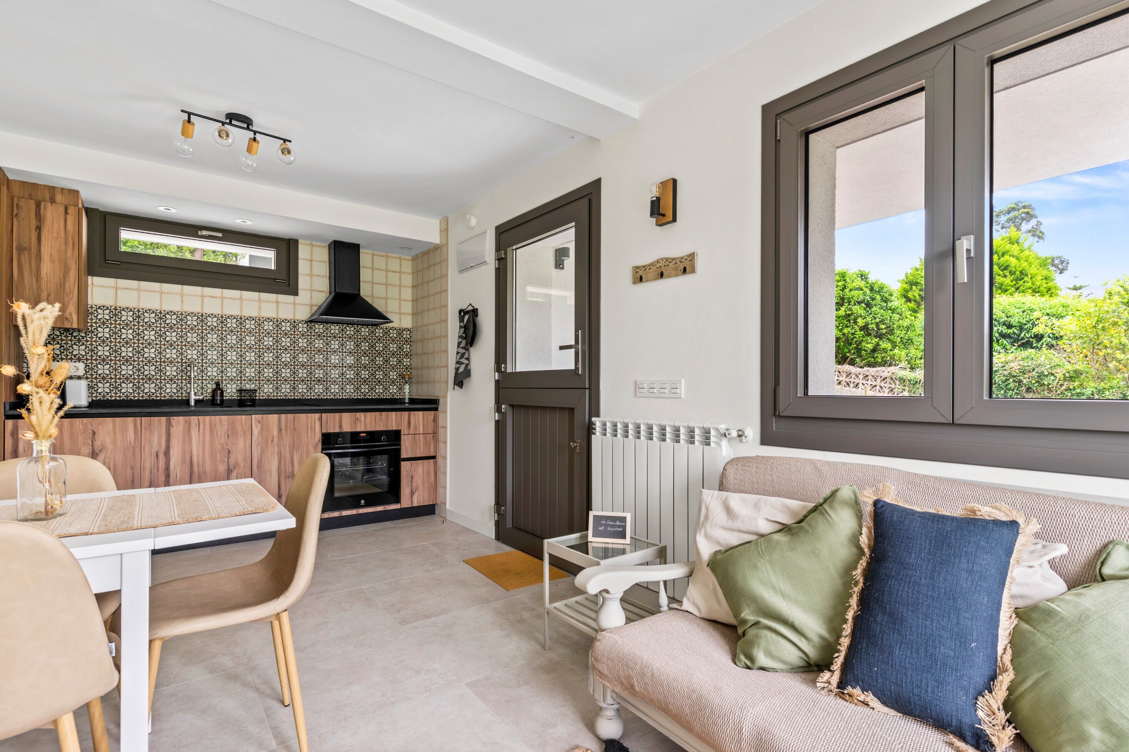 A compact living space with a kitchenette, a dining area, and a sofa with cushions.