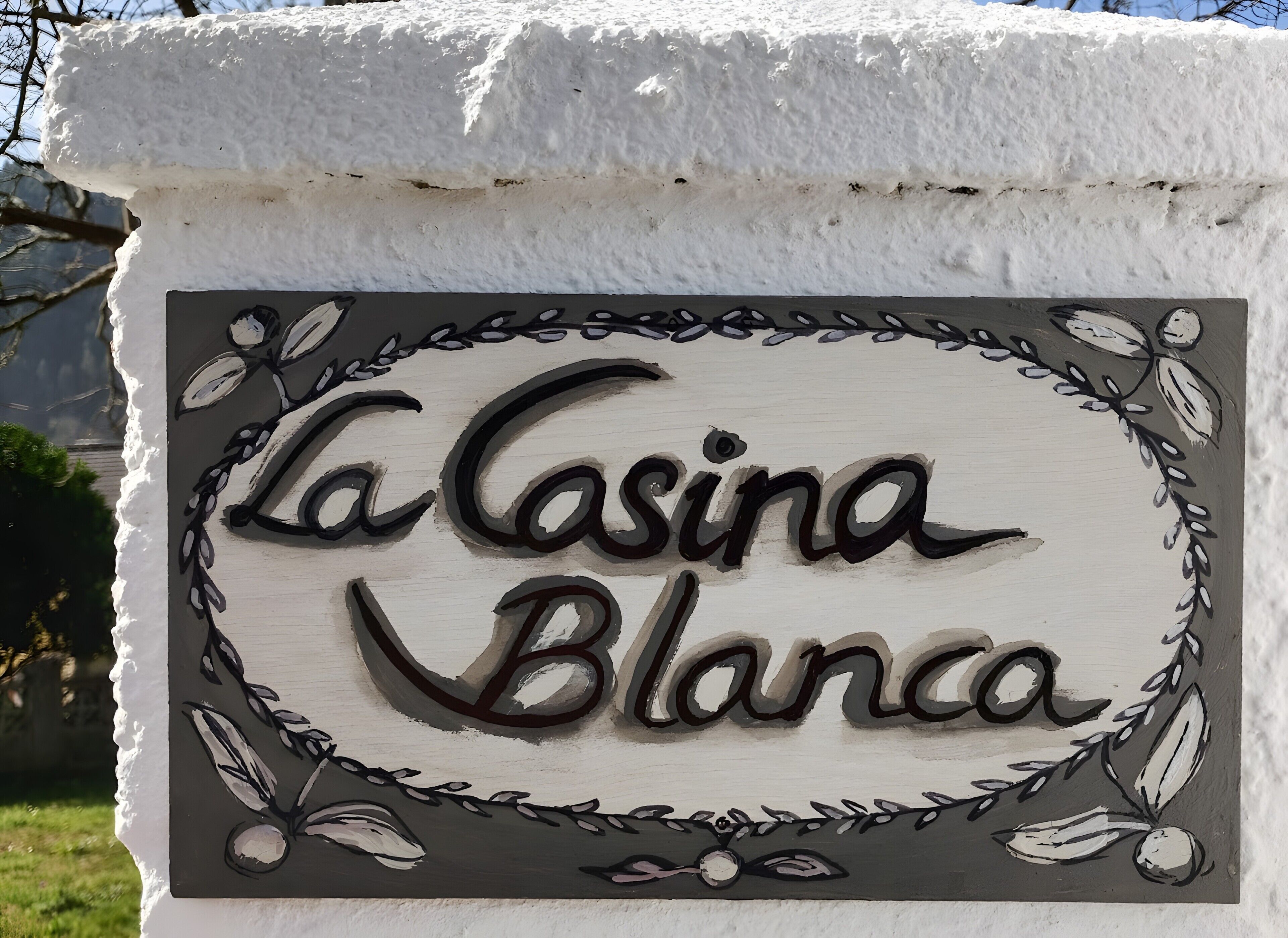 A sign with the text 'La Casina Blanca' surrounded by a decorative border.