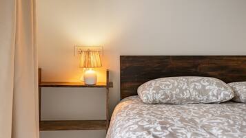 Een slaapkamer met een bed, een bedlampje, een nachtkastje en een stopcontact.